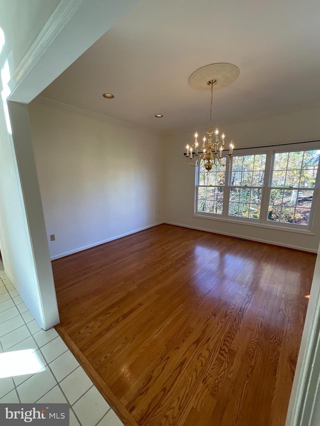 unfurnished room with light wood-type flooring, ornamental molding, and an inviting chandelier