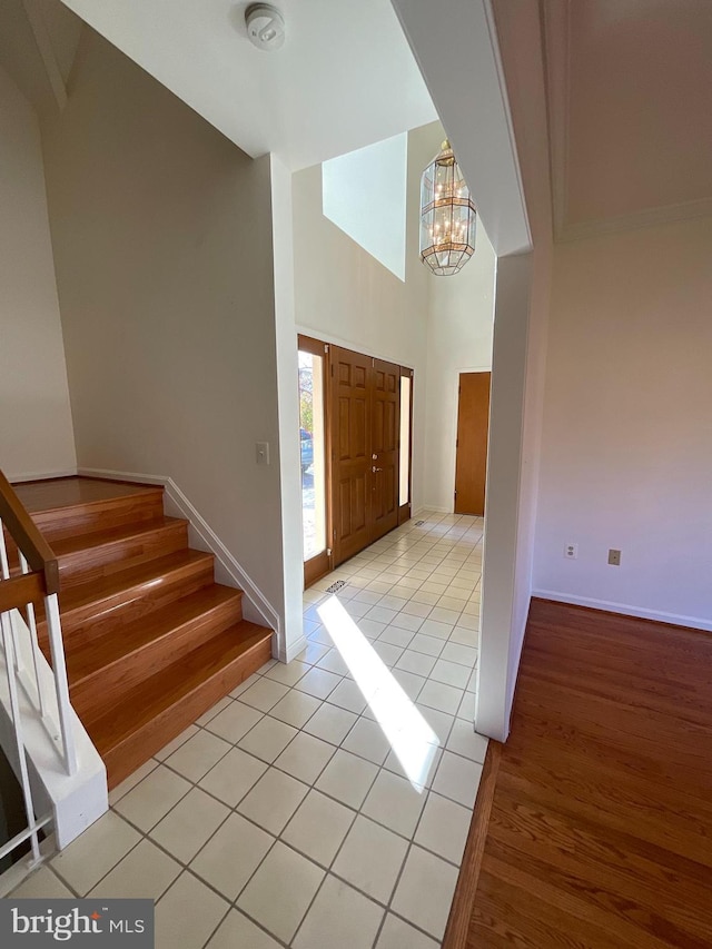 entrance foyer with light hardwood / wood-style flooring, a towering ceiling, and a notable chandelier