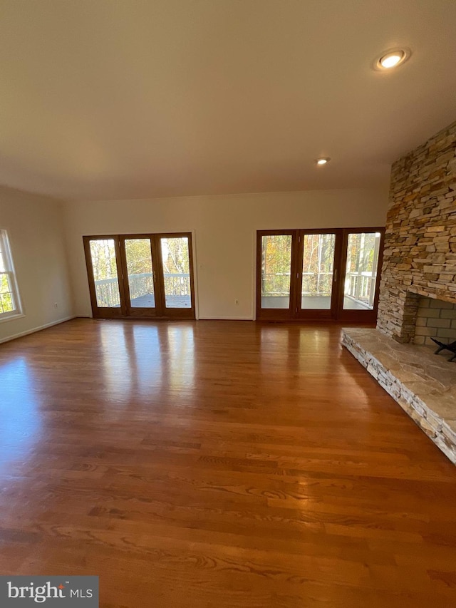 unfurnished living room with a stone fireplace and wood-type flooring