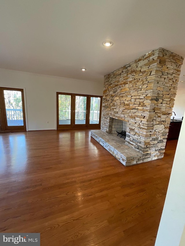 unfurnished living room featuring hardwood / wood-style floors, a stone fireplace, and a wealth of natural light