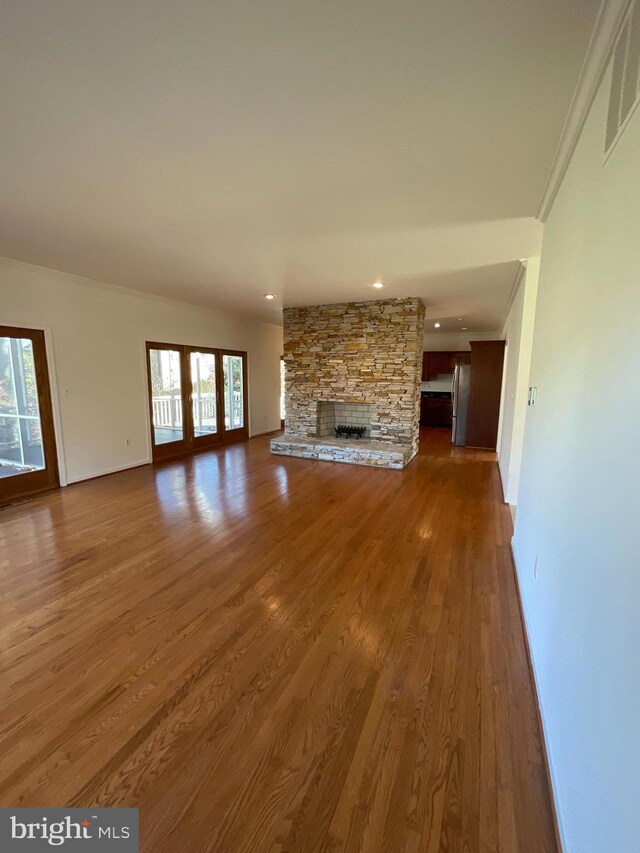 unfurnished living room with a fireplace, wood-type flooring, and ornamental molding