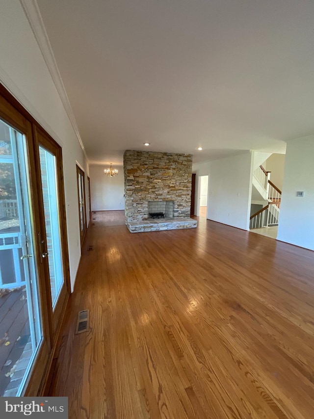 unfurnished living room featuring a fireplace, crown molding, hardwood / wood-style floors, and a chandelier