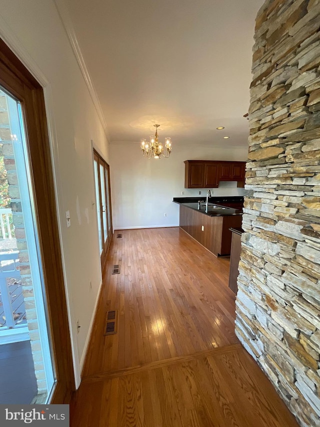 kitchen with dark wood-type flooring, an inviting chandelier, decorative light fixtures, a kitchen bar, and ornamental molding