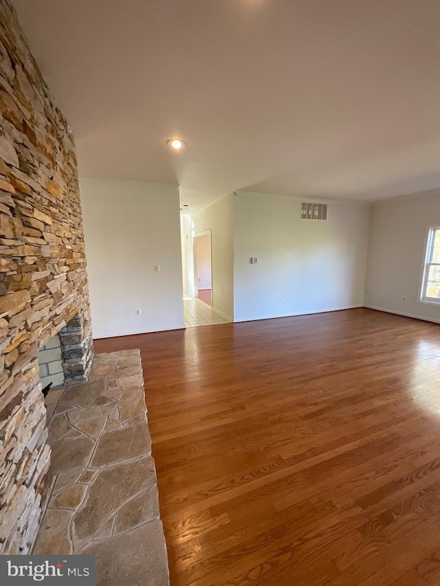 unfurnished living room with hardwood / wood-style floors and a stone fireplace