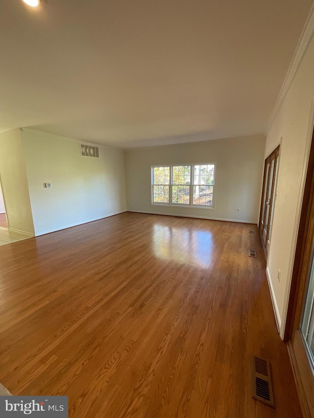 spare room with wood-type flooring and crown molding