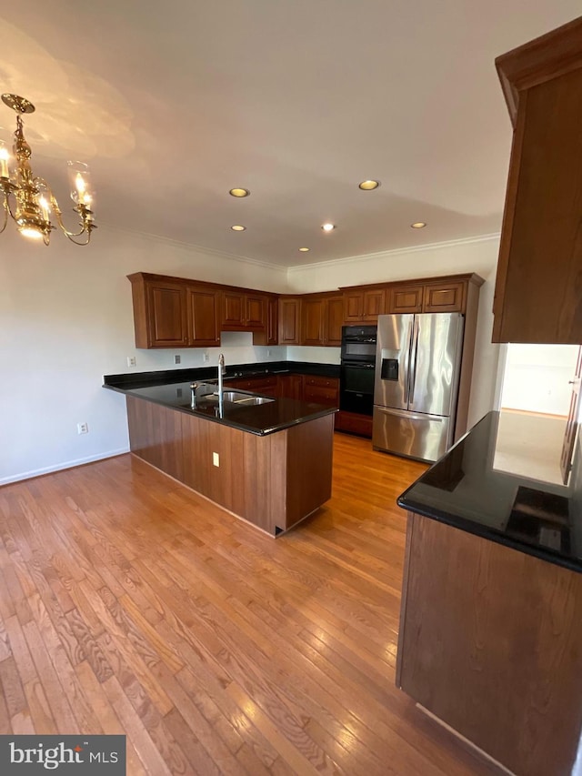 kitchen with ornamental molding, sink, stainless steel fridge with ice dispenser, light hardwood / wood-style floors, and an island with sink