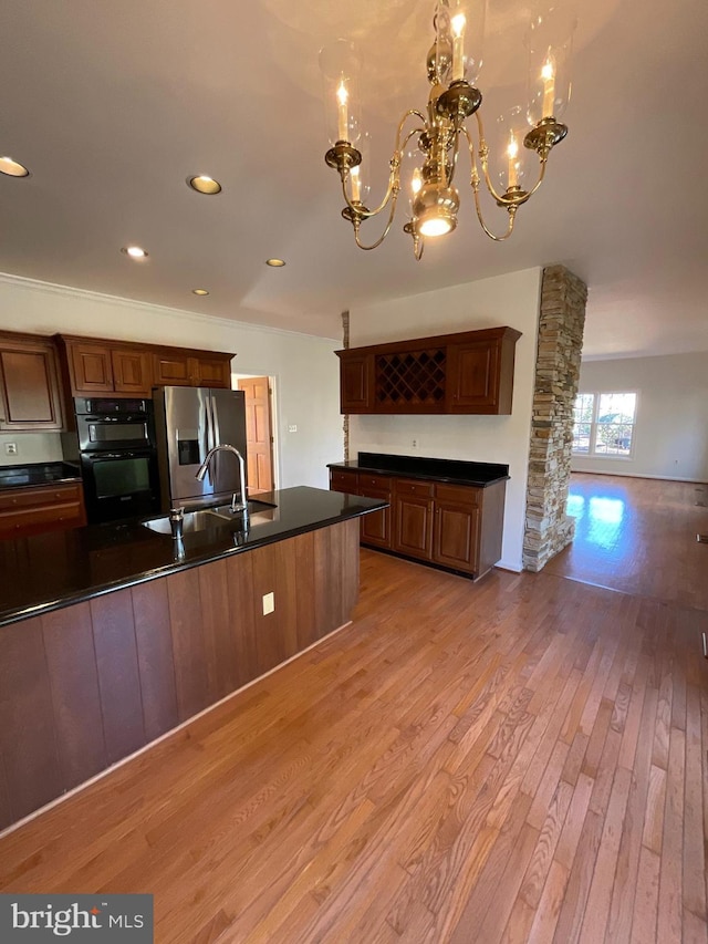 kitchen with stainless steel fridge, light hardwood / wood-style flooring, a chandelier, and sink