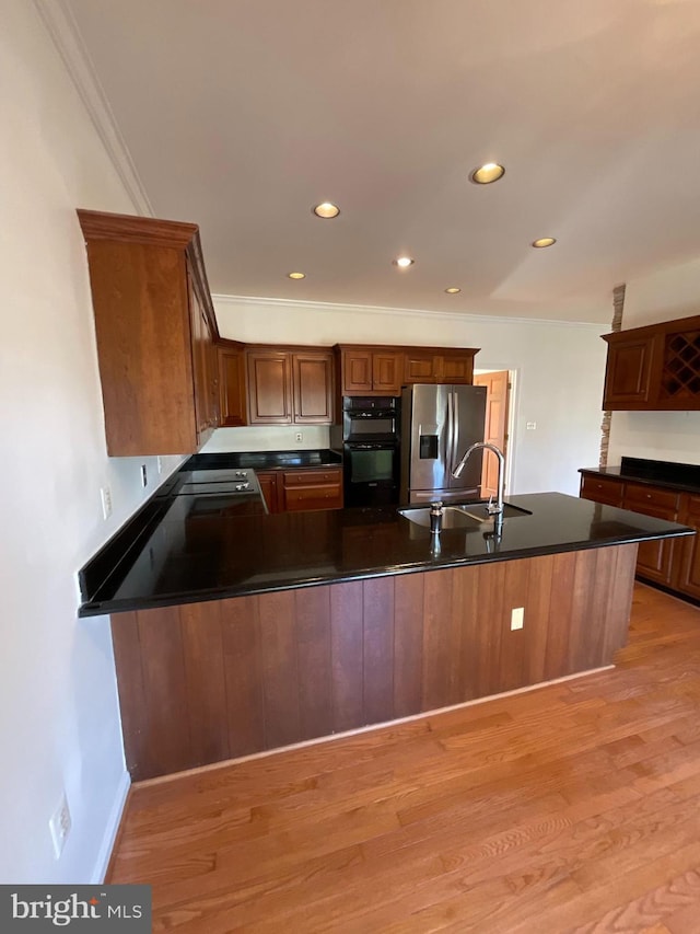 kitchen featuring sink, stainless steel fridge with ice dispenser, light hardwood / wood-style flooring, kitchen peninsula, and crown molding