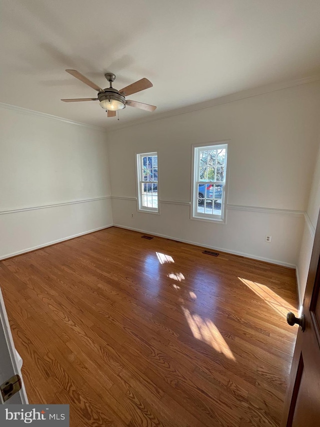 empty room with ceiling fan, hardwood / wood-style floors, and ornamental molding