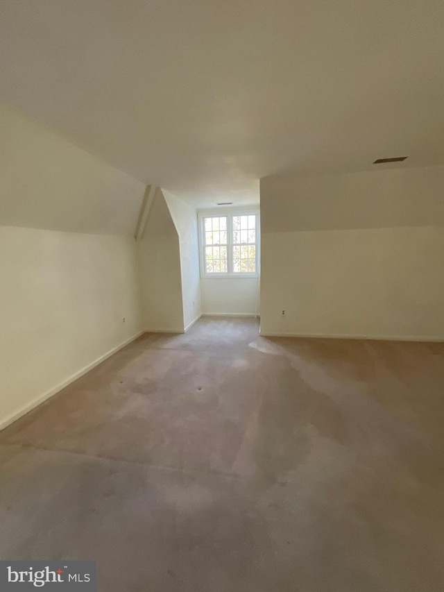 additional living space featuring light carpet and vaulted ceiling