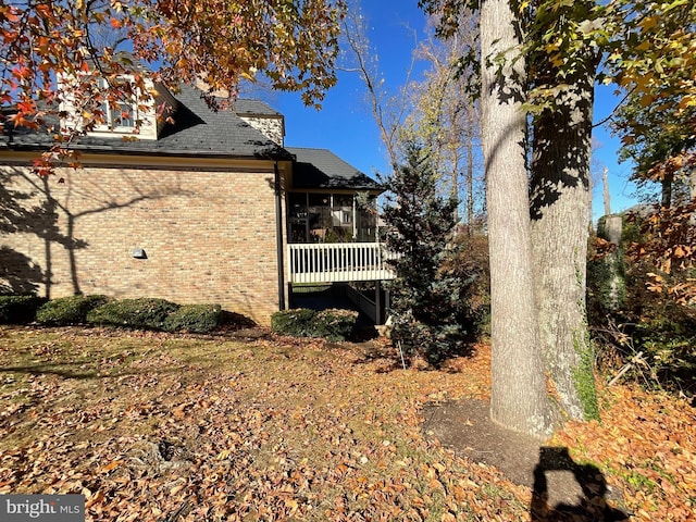 view of side of property with a sunroom and a wooden deck