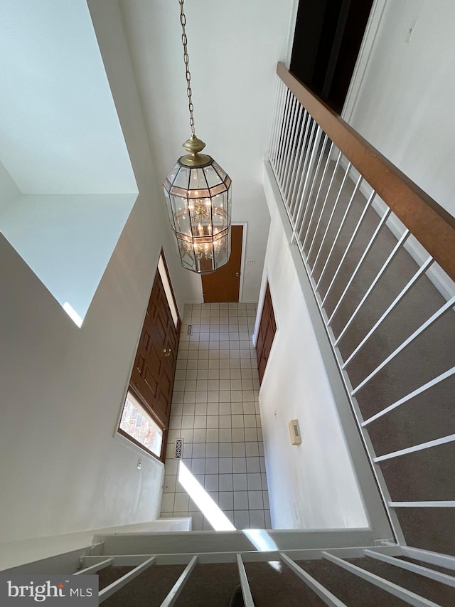 stairs featuring a chandelier, a towering ceiling, and tile patterned flooring