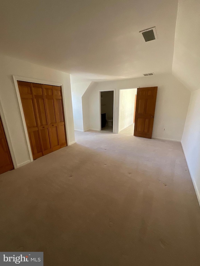 additional living space with light colored carpet and vaulted ceiling