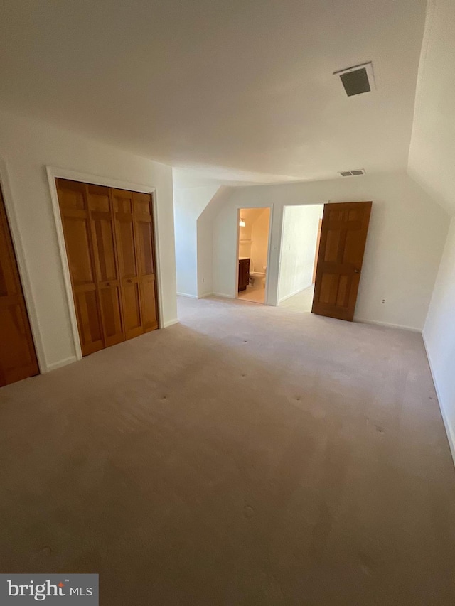 bonus room with light colored carpet and vaulted ceiling