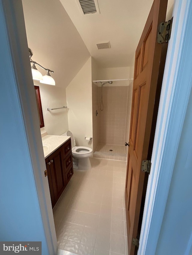 bathroom featuring toilet, a tile shower, vanity, and tile patterned floors