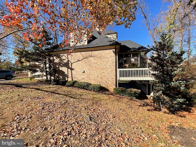 view of side of property featuring a sunroom and a deck