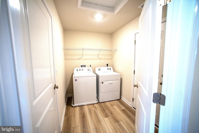 laundry area with separate washer and dryer and light hardwood / wood-style floors