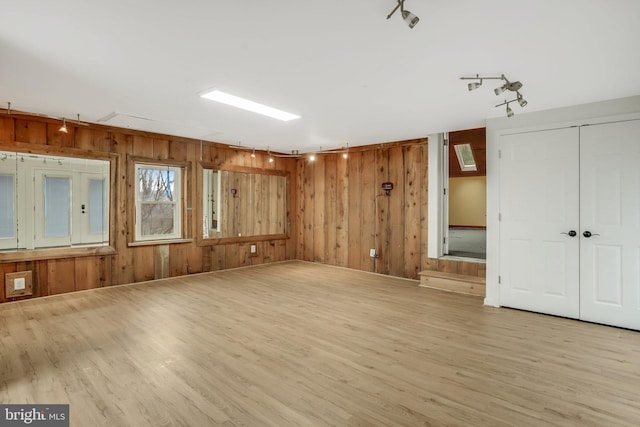 spare room with wooden walls and light wood-type flooring