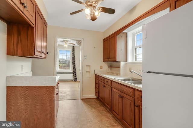 kitchen with sink, radiator heating unit, ceiling fan, and white fridge