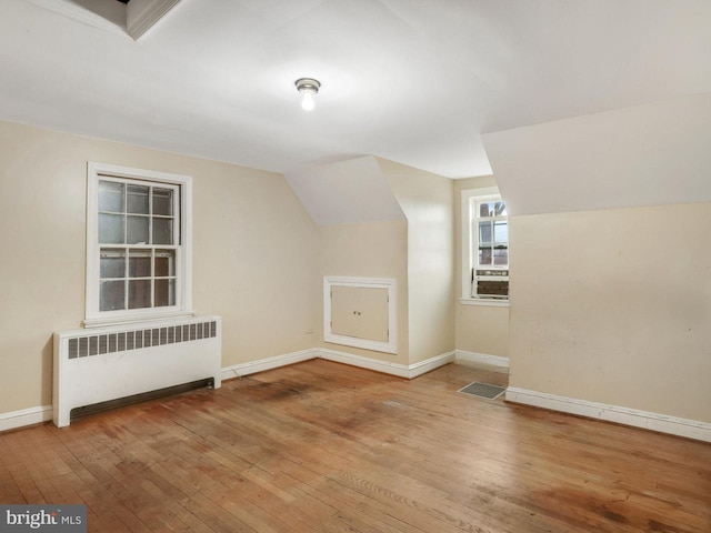 bonus room featuring lofted ceiling, radiator, and light hardwood / wood-style flooring