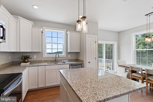 kitchen with a center island, sink, hardwood / wood-style flooring, a wealth of natural light, and white cabinetry