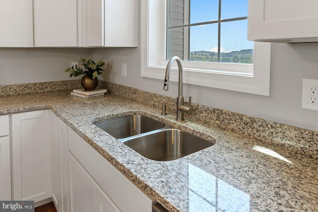 kitchen featuring light stone countertops, a mountain view, white cabinetry, and sink