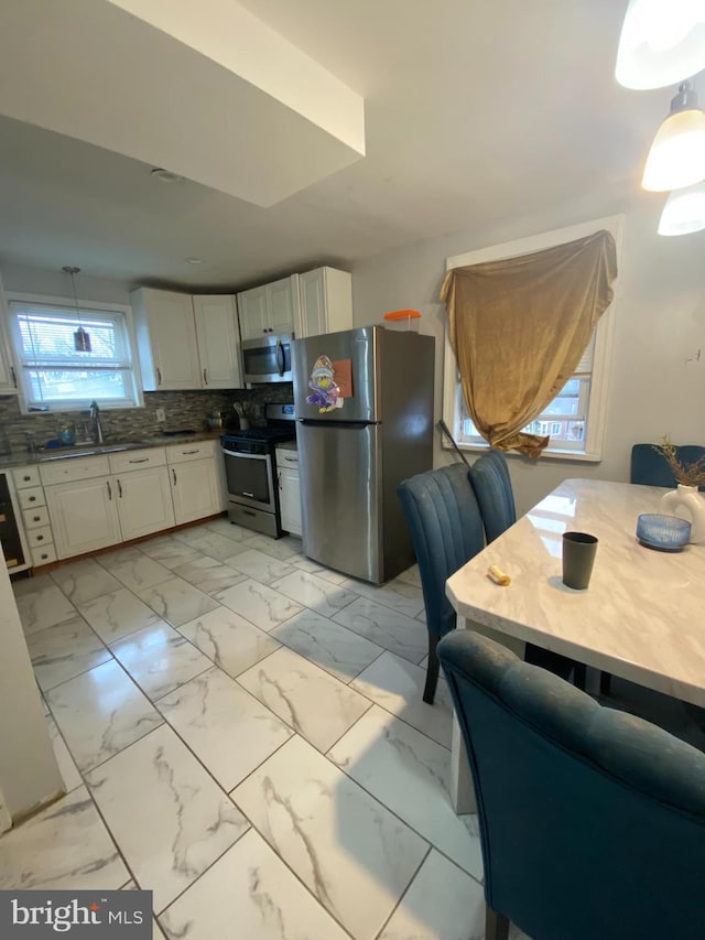 kitchen featuring appliances with stainless steel finishes, backsplash, decorative light fixtures, and sink