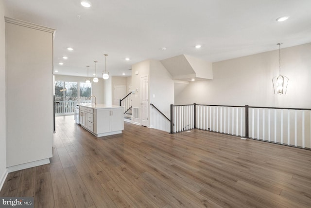 interior space featuring sink, hanging light fixtures, dark hardwood / wood-style flooring, a chandelier, and a center island with sink