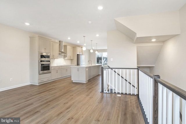 kitchen featuring backsplash, a kitchen island with sink, wall chimney exhaust hood, decorative light fixtures, and stainless steel appliances