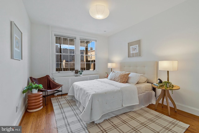 bedroom with hardwood / wood-style flooring and radiator heating unit