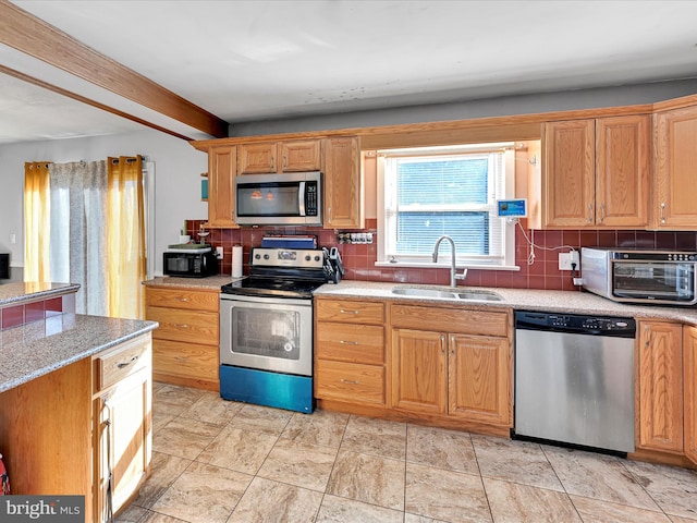 kitchen featuring appliances with stainless steel finishes, tasteful backsplash, light stone counters, and sink