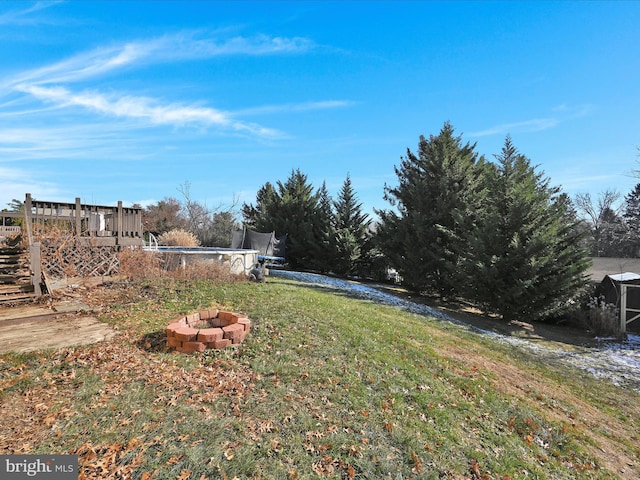 view of yard with a deck and an outdoor fire pit