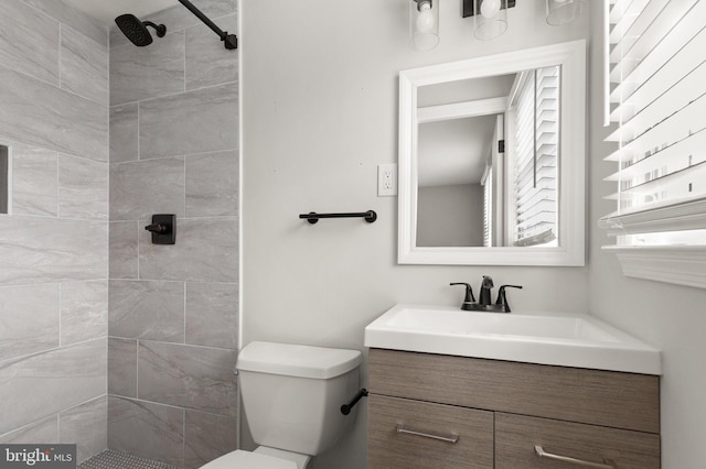 bathroom featuring vanity, toilet, and a tile shower