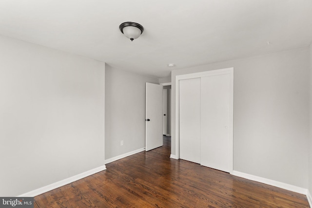 unfurnished bedroom with dark hardwood / wood-style flooring and a closet