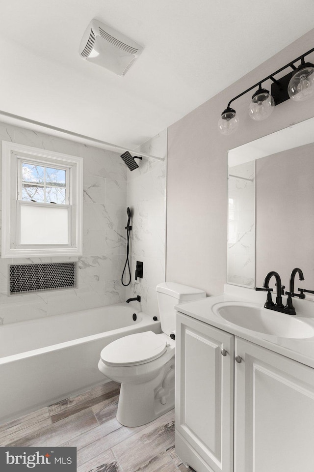 full bathroom featuring hardwood / wood-style floors, vanity, toilet, and tiled shower / bath combo