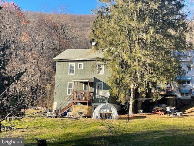 rear view of house with a lawn and a wooden deck