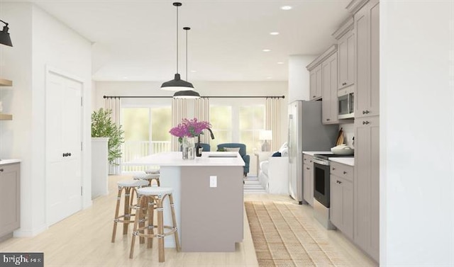 kitchen featuring a breakfast bar, appliances with stainless steel finishes, gray cabinets, and a kitchen island with sink