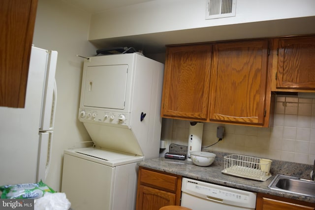 laundry area with stacked washer / drying machine and sink