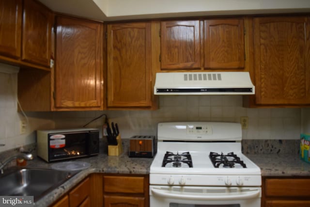 kitchen with backsplash, extractor fan, white gas range, and sink