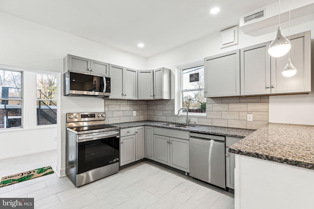 kitchen featuring sink, hanging light fixtures, decorative backsplash, a healthy amount of sunlight, and stainless steel appliances