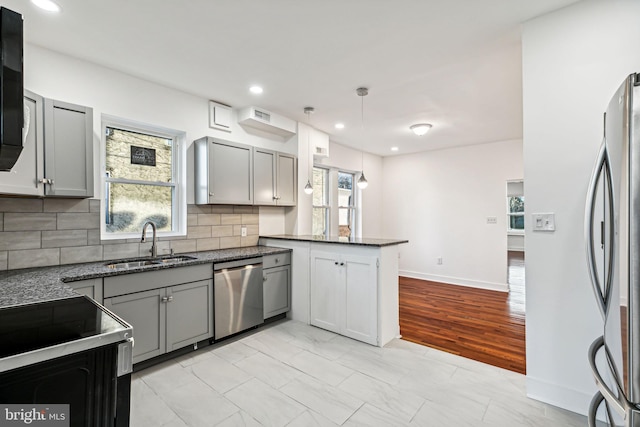 kitchen with kitchen peninsula, sink, gray cabinets, and stainless steel appliances