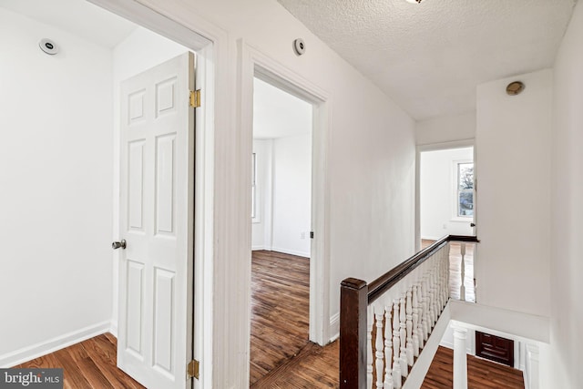 corridor with a textured ceiling and hardwood / wood-style flooring