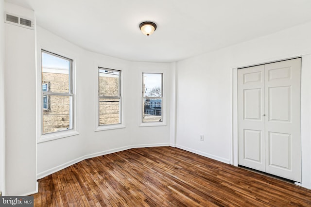 unfurnished bedroom with dark hardwood / wood-style flooring and a closet