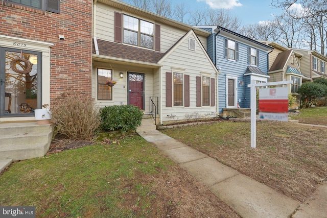 multi unit property with a shingled roof and a front lawn