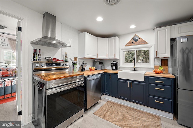 kitchen with white cabinets, butcher block countertops, and appliances with stainless steel finishes