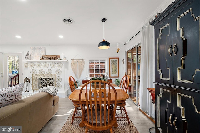 dining area with a wealth of natural light, a fireplace, crown molding, and light wood-type flooring