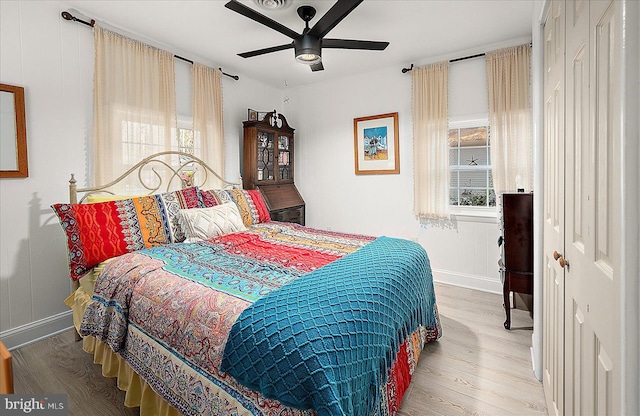 bedroom with multiple windows, ceiling fan, and light hardwood / wood-style floors