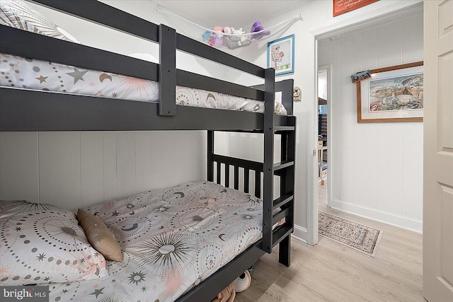 bedroom with light hardwood / wood-style flooring and wooden walls