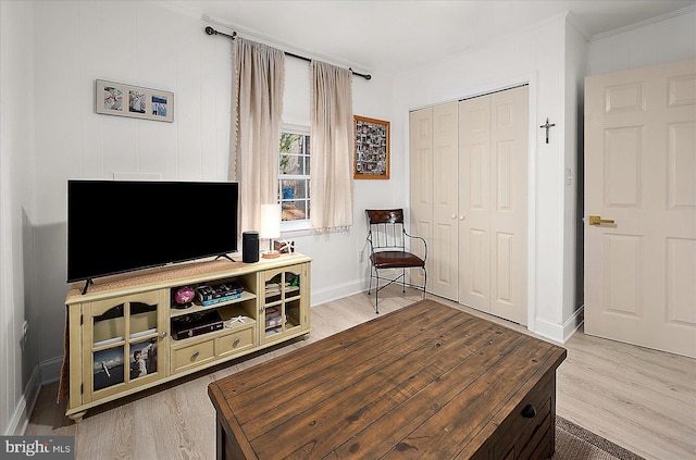 living area with crown molding and light wood-type flooring