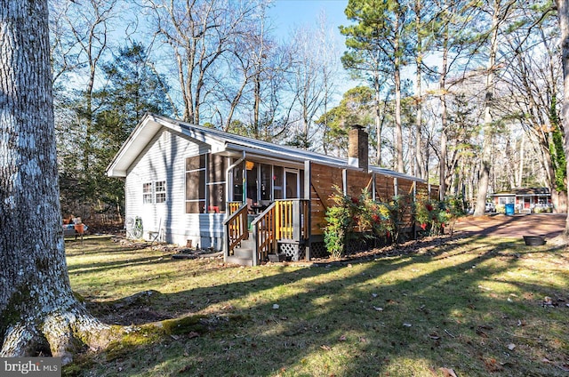 view of side of property with a sunroom and a lawn